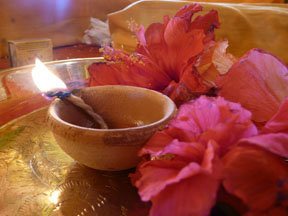 Hindu girl in temple holding lamp near gold statue